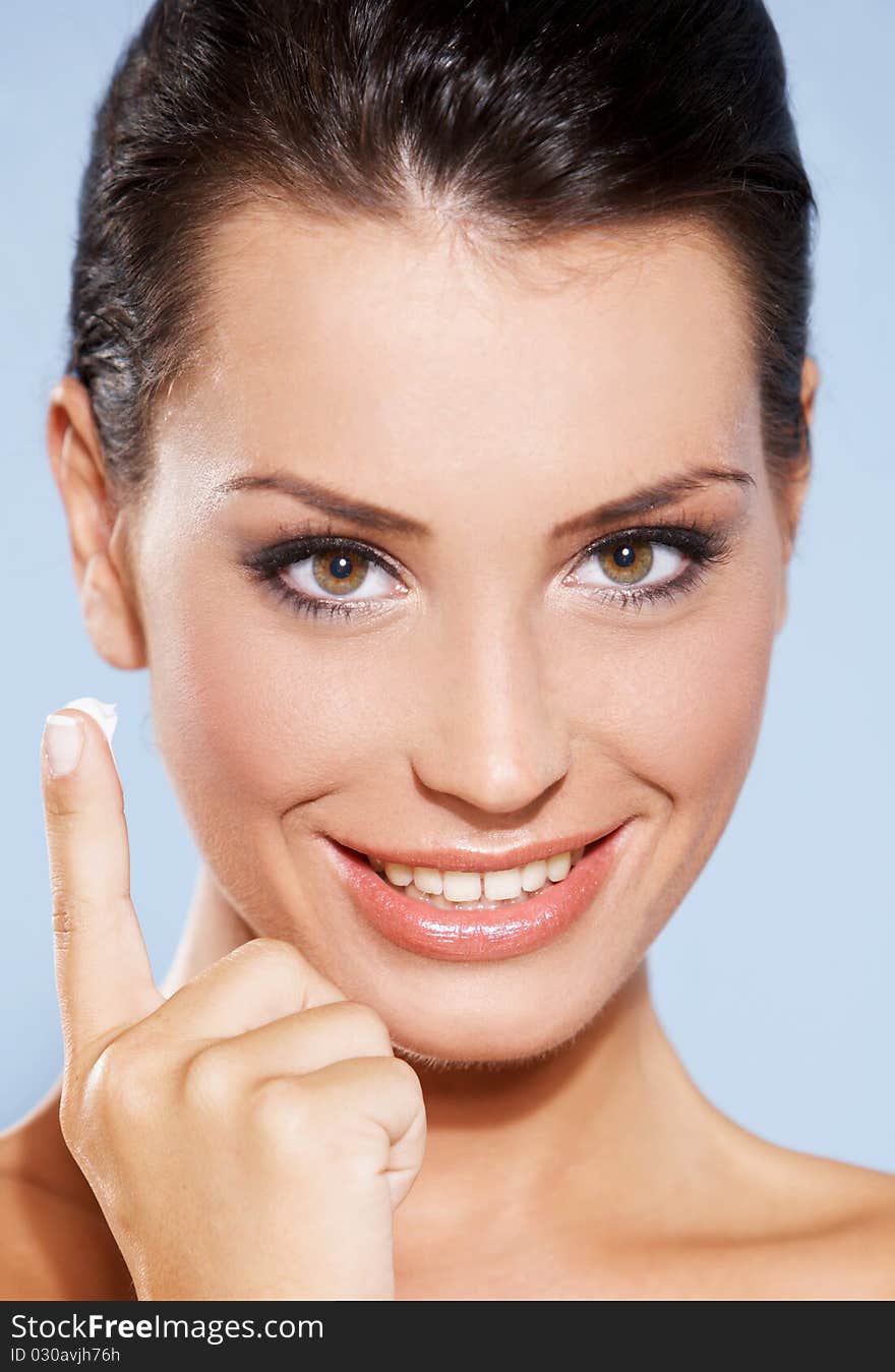 Portrait of beautiful woman, she has cream on her finger, isolated on blue. Portrait of beautiful woman, she has cream on her finger, isolated on blue