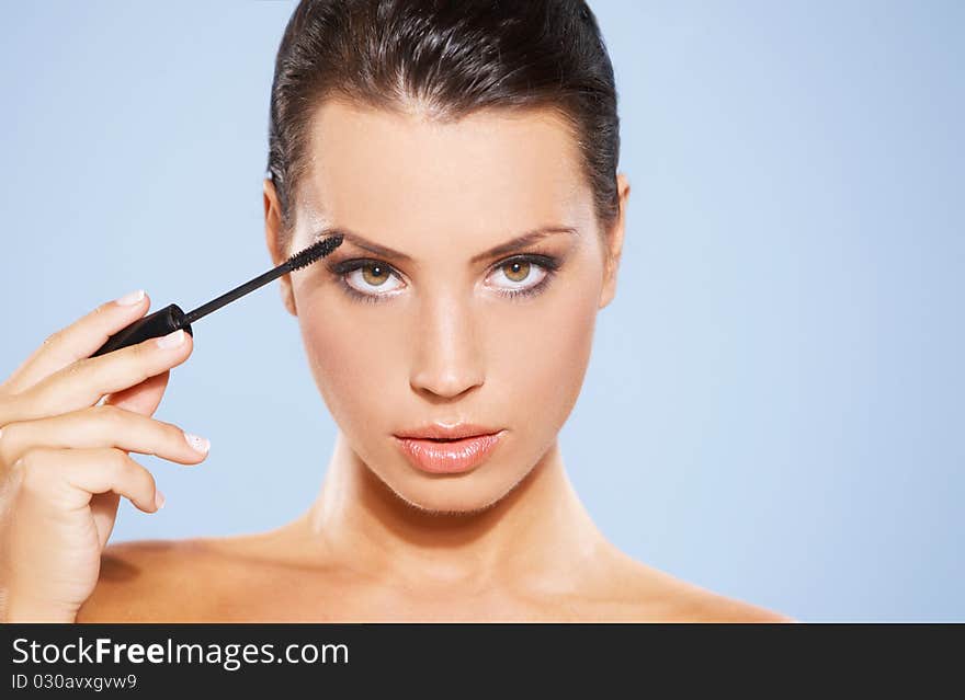 Portrait of beautiful woman she is doing makeup, isolated on blue background. Portrait of beautiful woman she is doing makeup, isolated on blue background