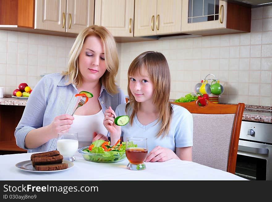 Mom and young daughter eating breakfast together in the kitchen