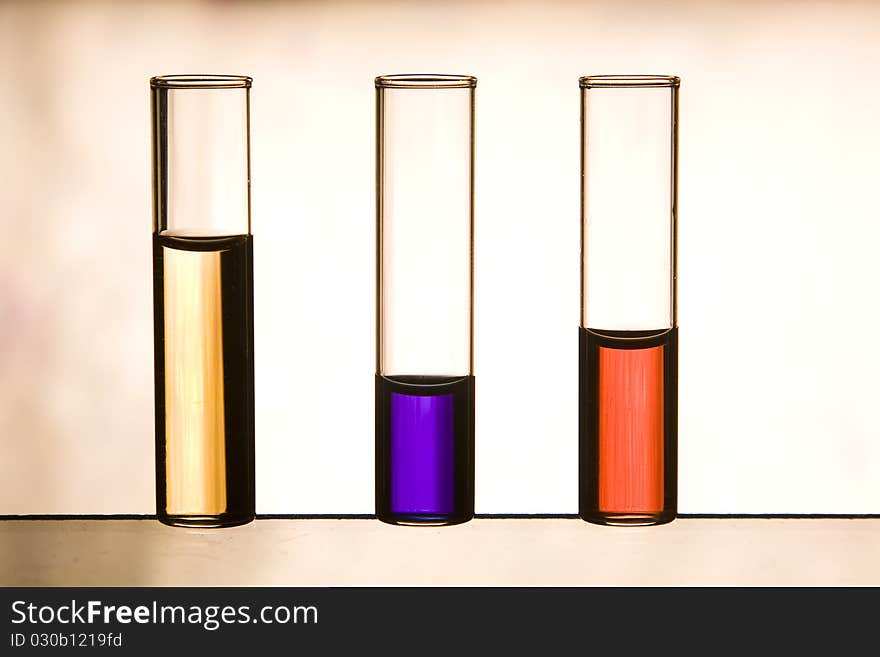 Three vials with red, purple and yellow color liquids in backlight. Three vials with red, purple and yellow color liquids in backlight