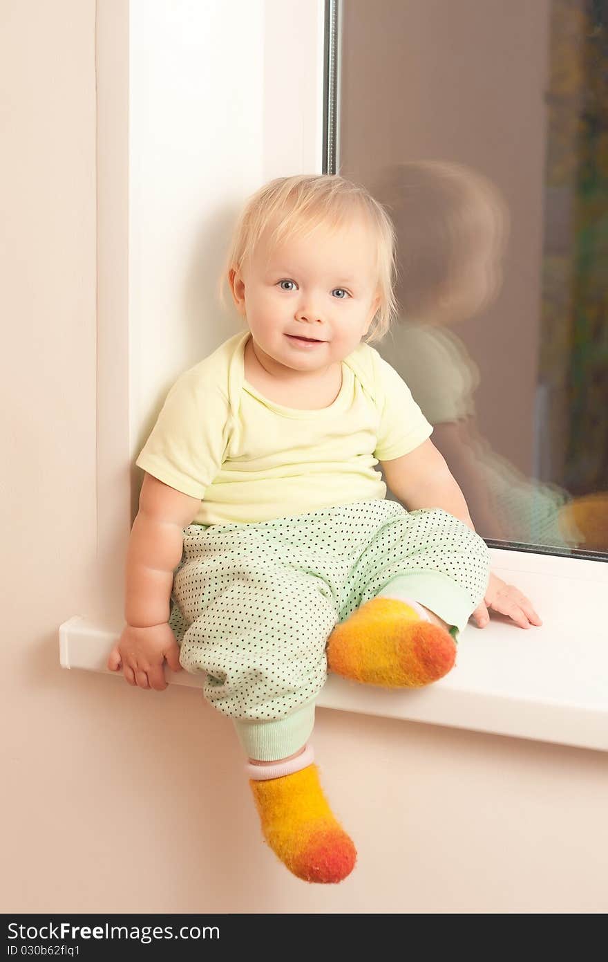 Adorable toddler girl sitting on the window sill