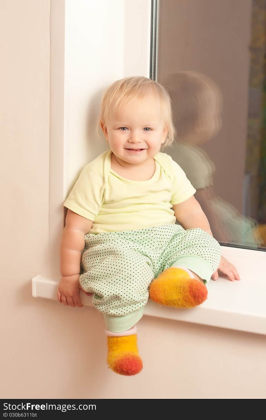 Adorable toddler girl sitting on the window sill and smile. Adorable toddler girl sitting on the window sill and smile