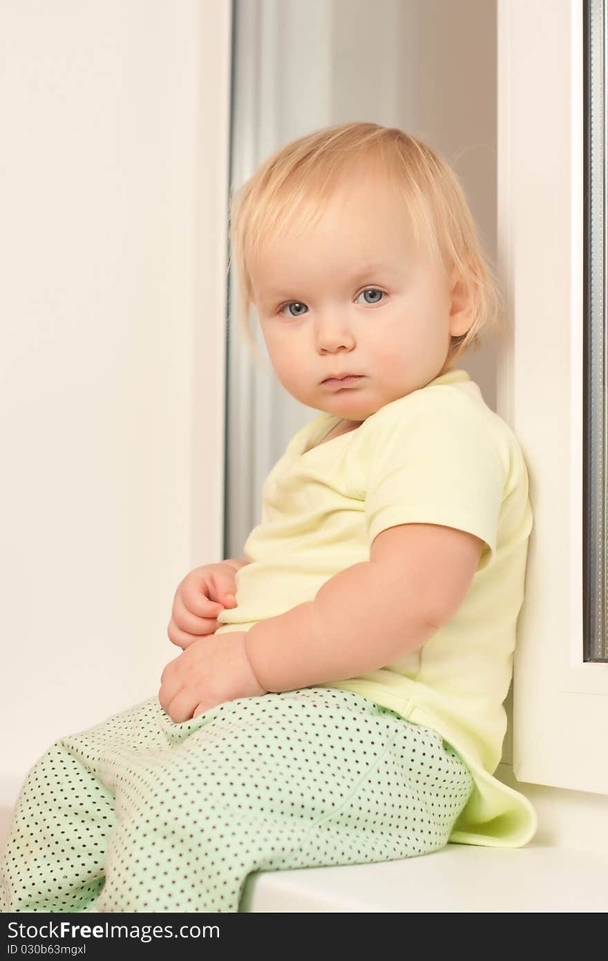 Adorable toddler girl sitting on the window sill