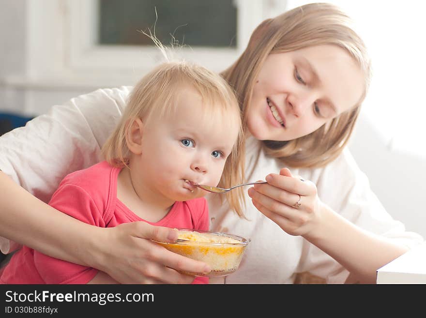 Young Mother Feeding Daughter With Porridge