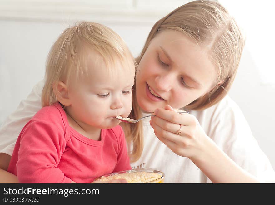 Mother feeding daughter with porridge