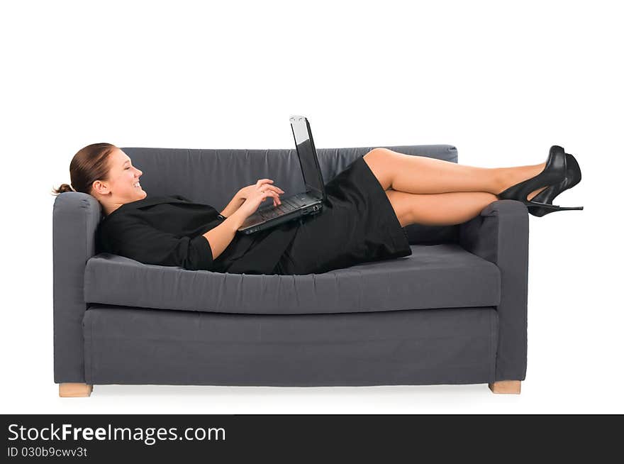 The businesswoman works behind the laptop lying on a sofa at office. The businesswoman works behind the laptop lying on a sofa at office.