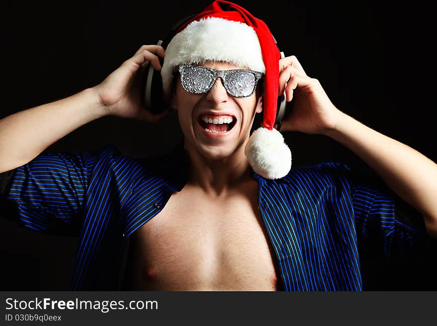 Portrait of a funny young man in Santa Claus hat and headphones. Christmas. Portrait of a funny young man in Santa Claus hat and headphones. Christmas.