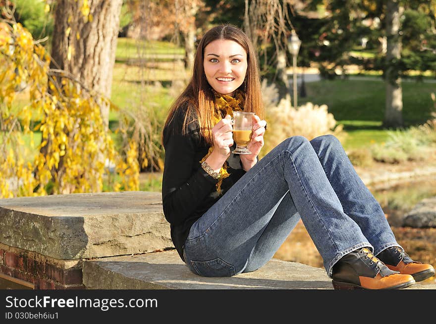 Young woman sipping coffee out on a bright fall day. Young woman sipping coffee out on a bright fall day