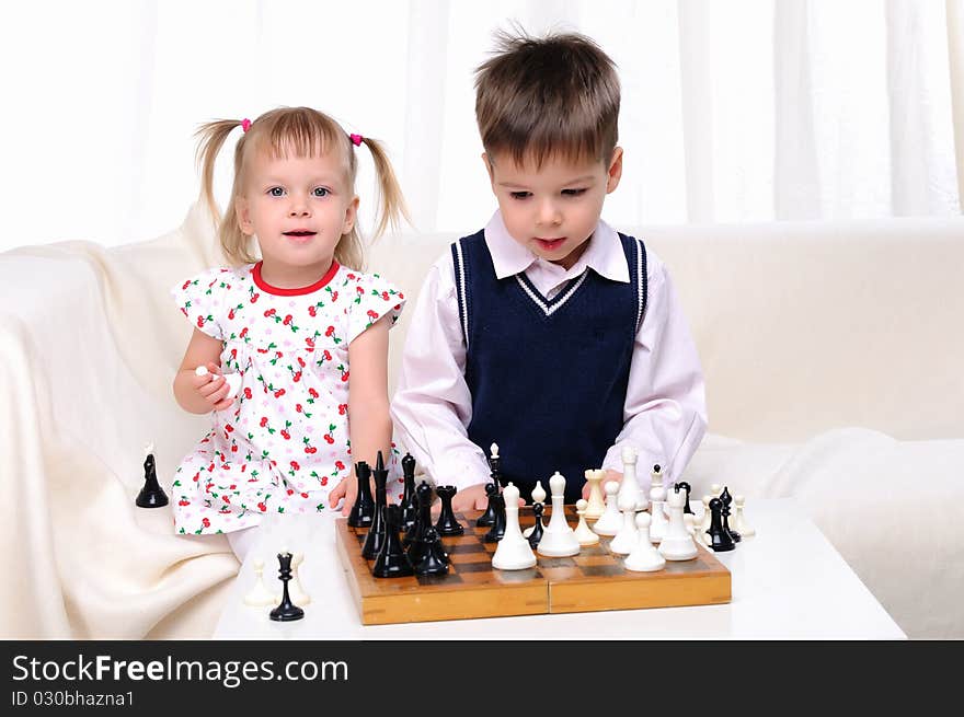 Brother and sister playing chess at a table