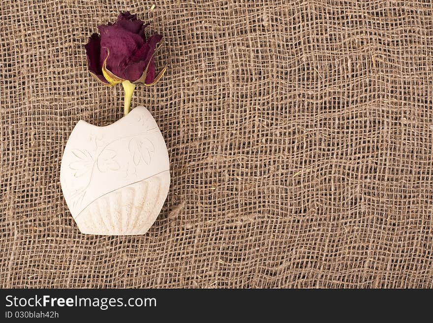 Withering rose in a crock on rough material