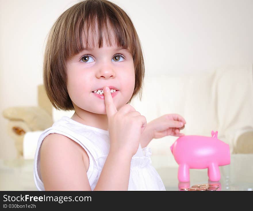 A little girl hides her money in the pig piggy bank.