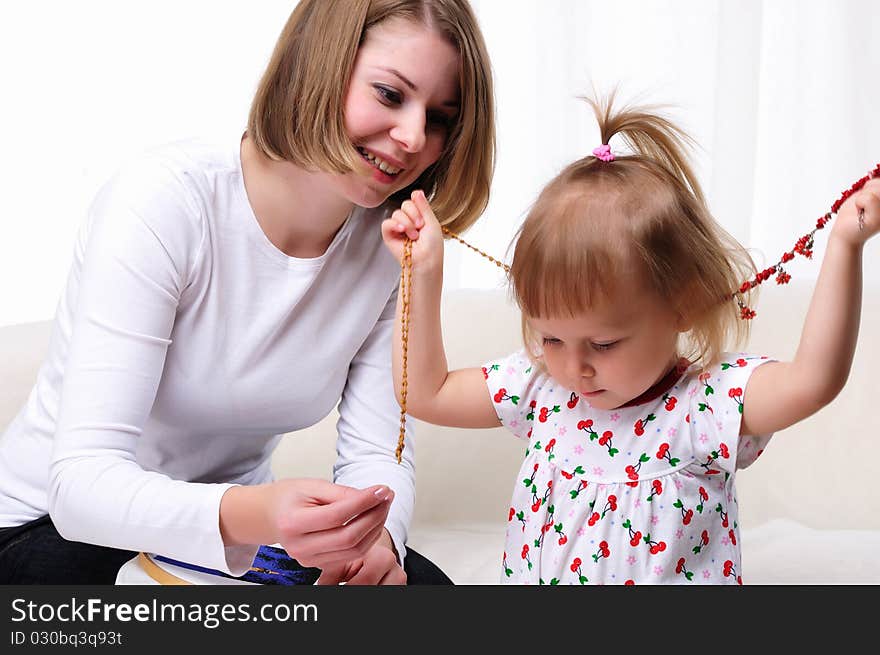 Young mother and her baby daughter spending time together. Dress up in costume jewelry.