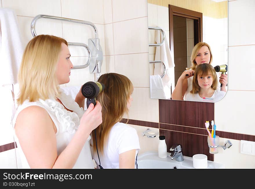 A young girl and her mother take care of the hair in his bathroom