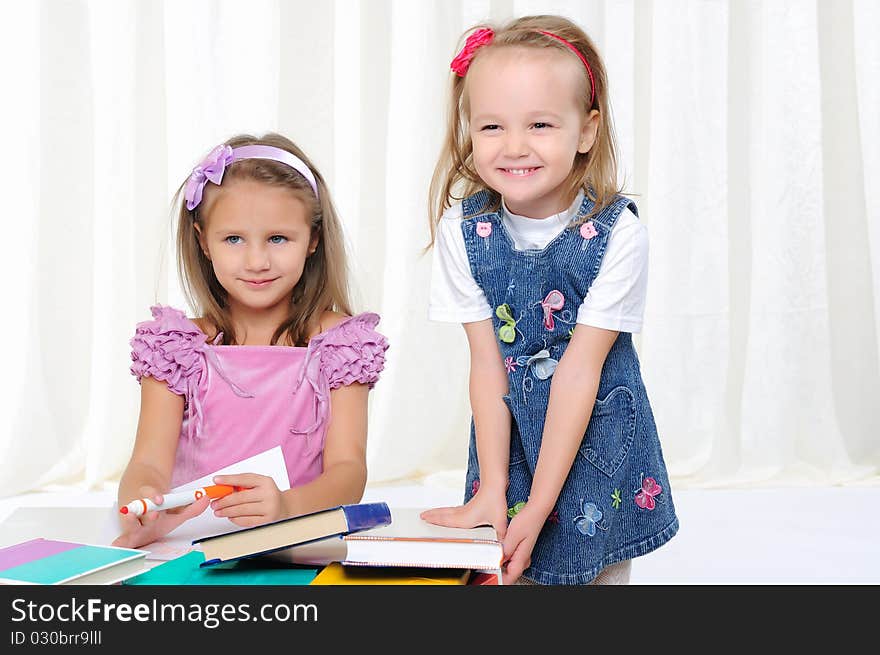 Little girls are studying literature. Reads a book while sitting at a white table.