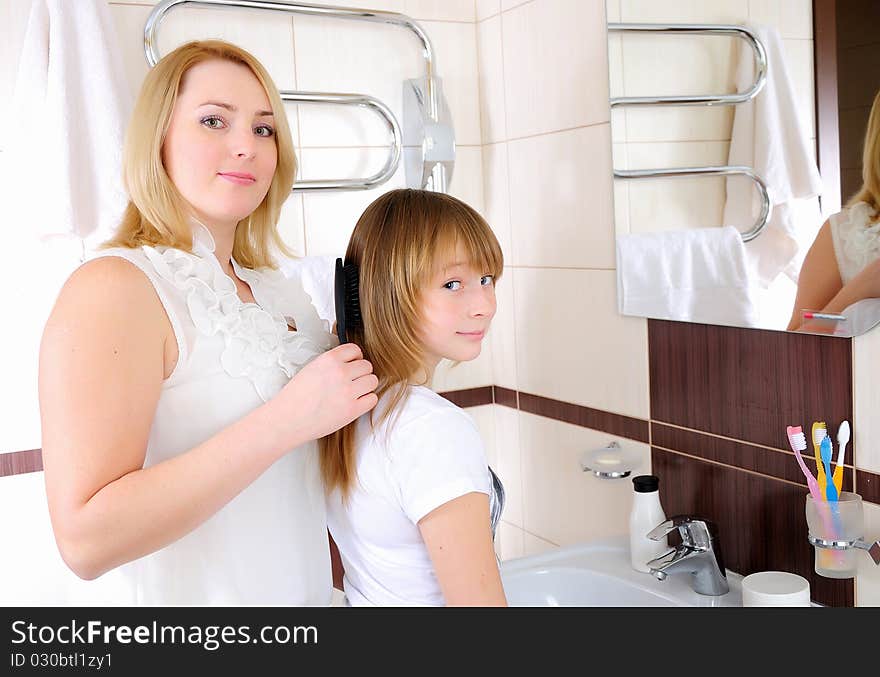 A young girl and her mother take care of the hair in his bathroom