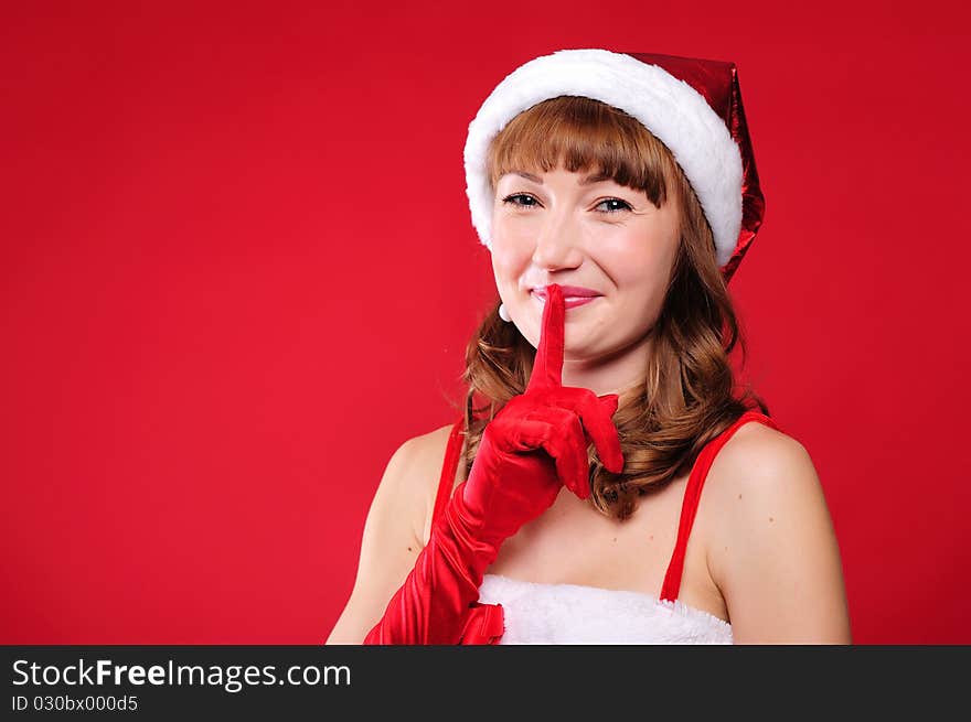 Portrait of a young girl dressed as Santa Claus on a red background. Happy New Year and Merry Christmas!