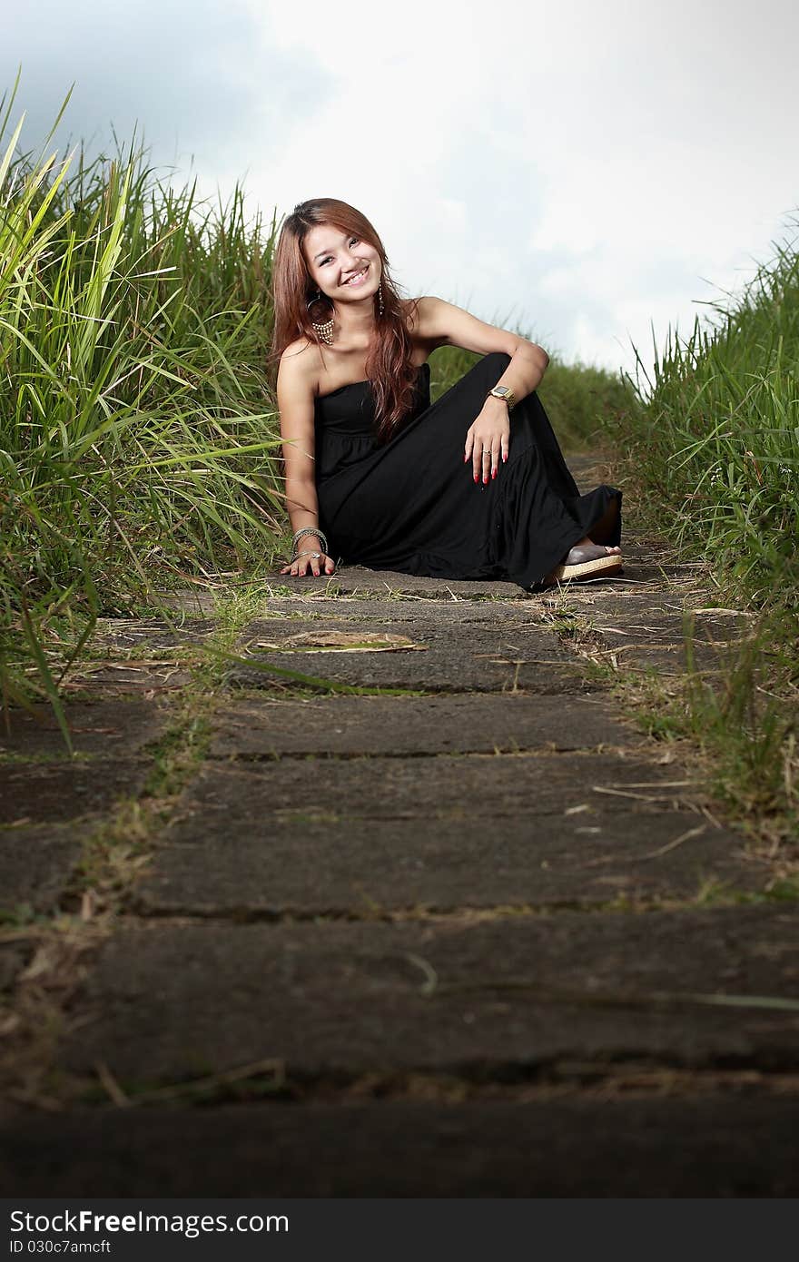 Young beautiful woman smiling outdoors in the meadow using black dress. Young beautiful woman smiling outdoors in the meadow using black dress