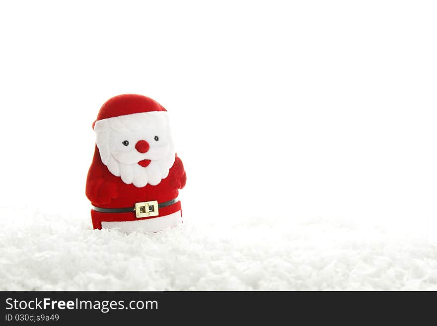 Red Santa Claus figurine stands on an artificial snow. Isolated on a white background. Red Santa Claus figurine stands on an artificial snow. Isolated on a white background