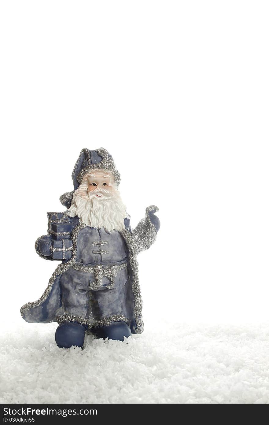 Blue Santa Claus figurine stands on an artificial snow. Isolated on a white background. Blue Santa Claus figurine stands on an artificial snow. Isolated on a white background