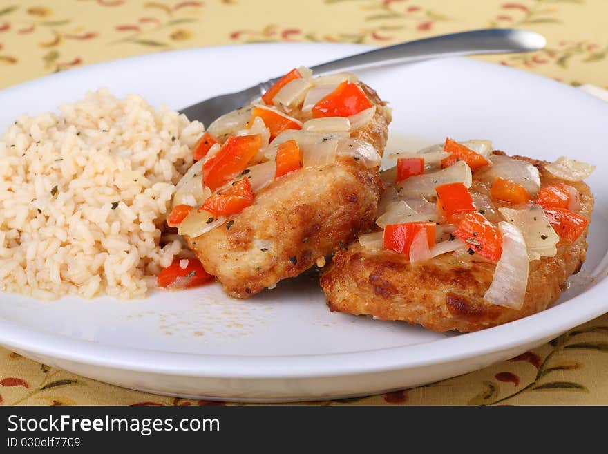 Pork cutlet meal topped with red peppers and onions with rice