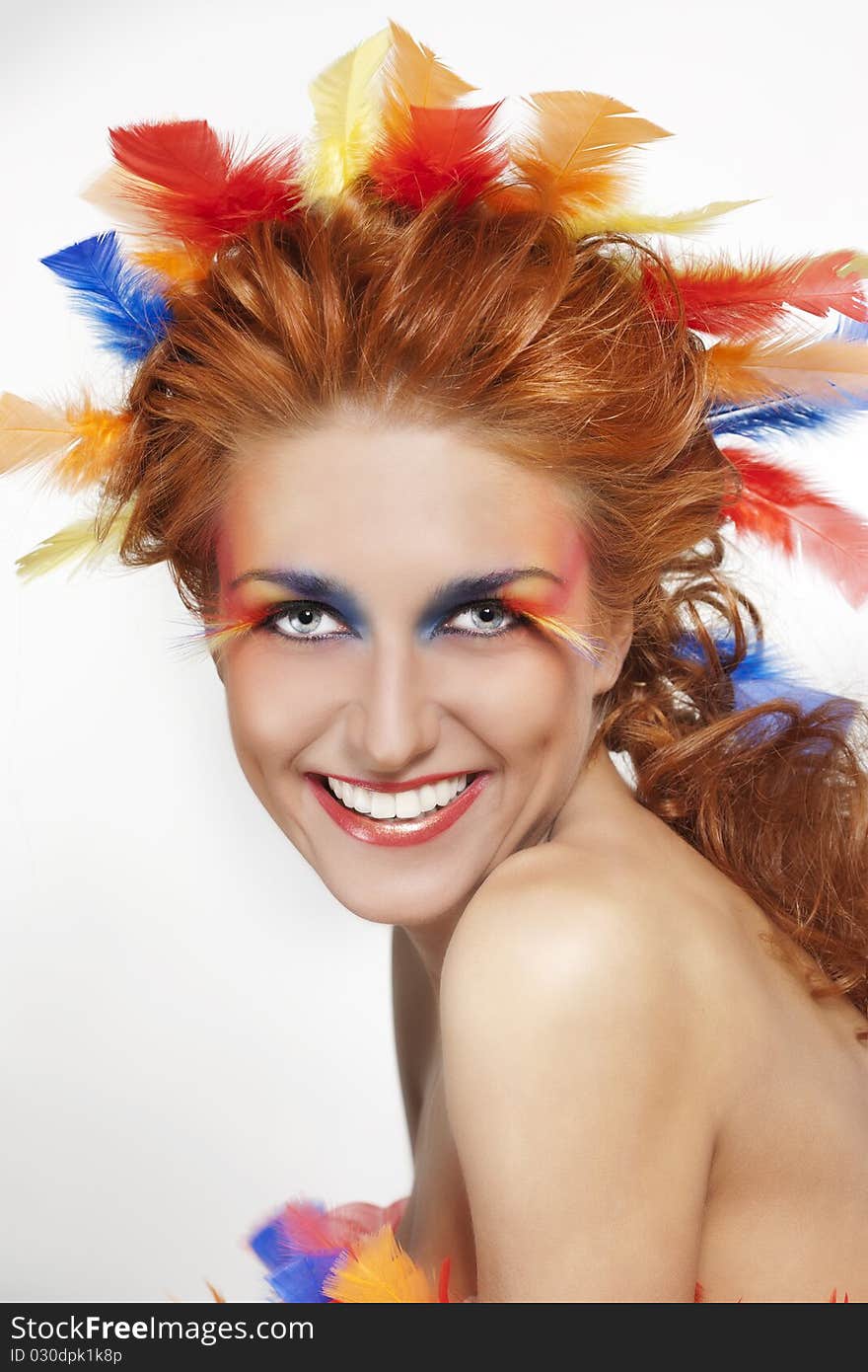 Beautiful woman with face framed in feathers with bright makeup and long faux lashes