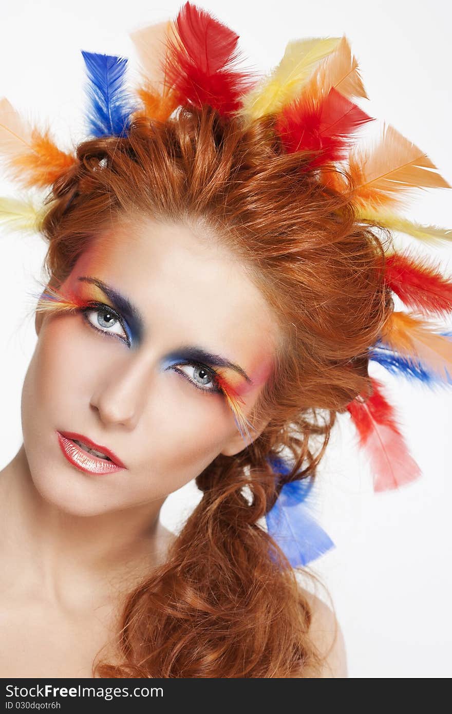 Beautiful woman with face framed in feathers with bright makeup and long faux lashes