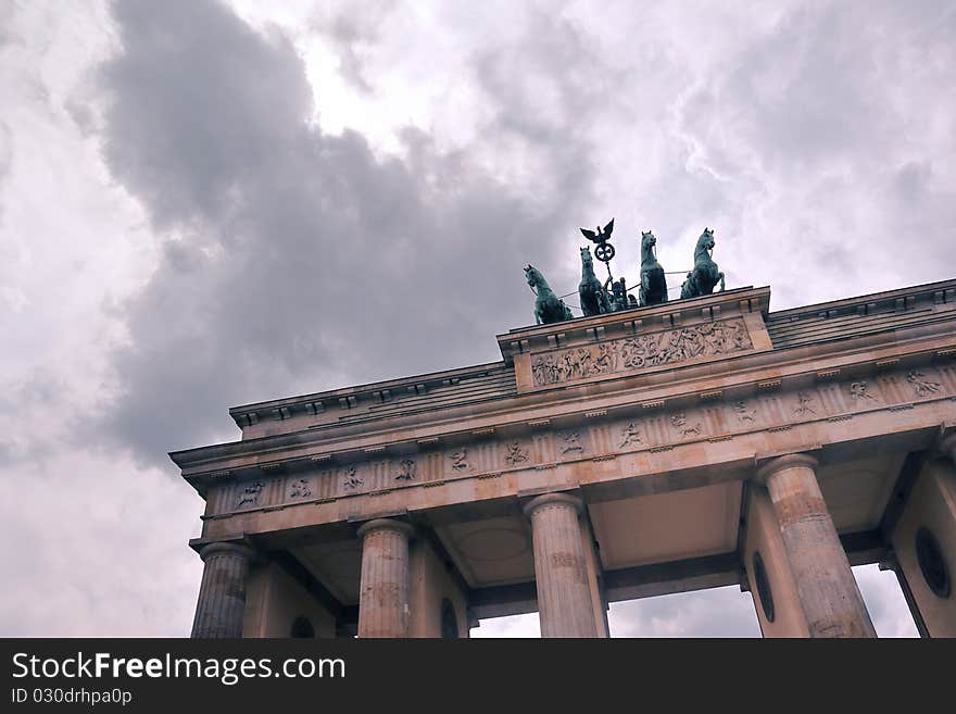 Fragment of famous Brandenburg Gate in  Berlin under dramatic cloudy sky. Fragment of famous Brandenburg Gate in  Berlin under dramatic cloudy sky