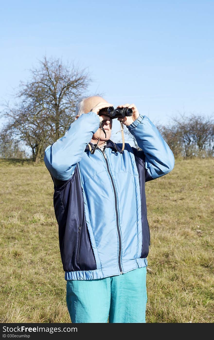 Senior man looking at with binoculars in the nature in Autumn. Senior man looking at with binoculars in the nature in Autumn