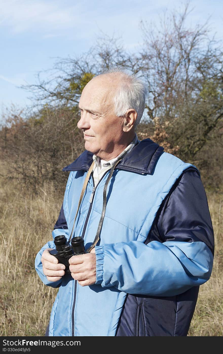 Senior man with binoculars in the nature in Autumn. Senior man with binoculars in the nature in Autumn