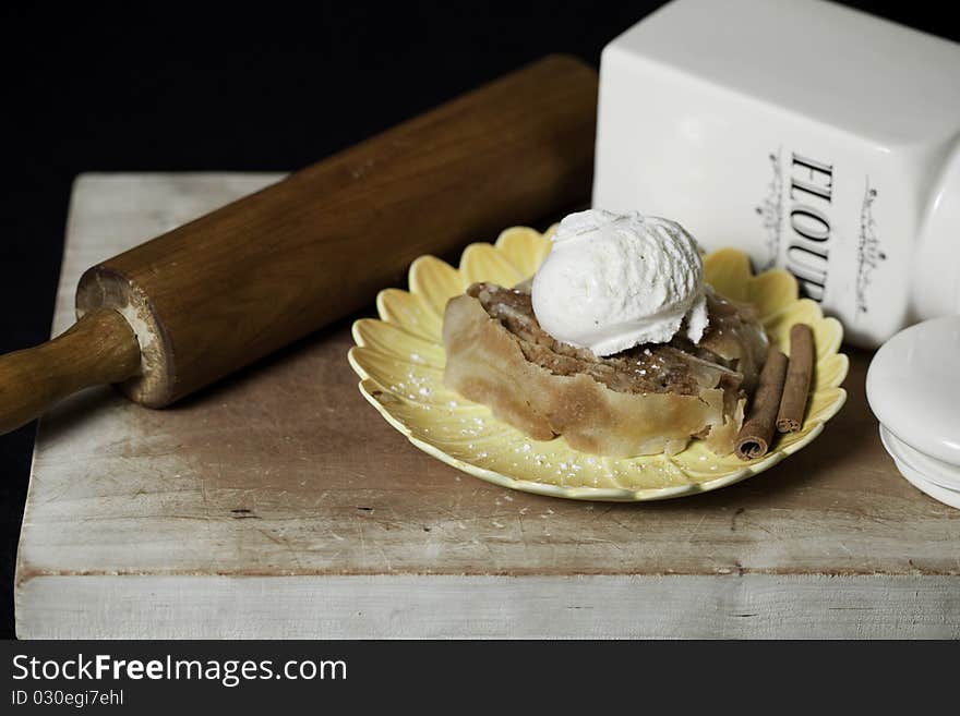 Apple Strudel with vanilla ice cream on plate with powdered cinnamon and powered sugar.