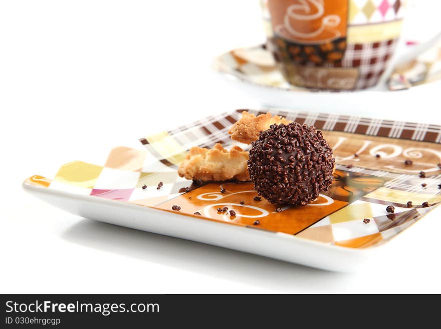 A chocolate praline on a plate with a piece of cookie. A chocolate praline on a plate with a piece of cookie