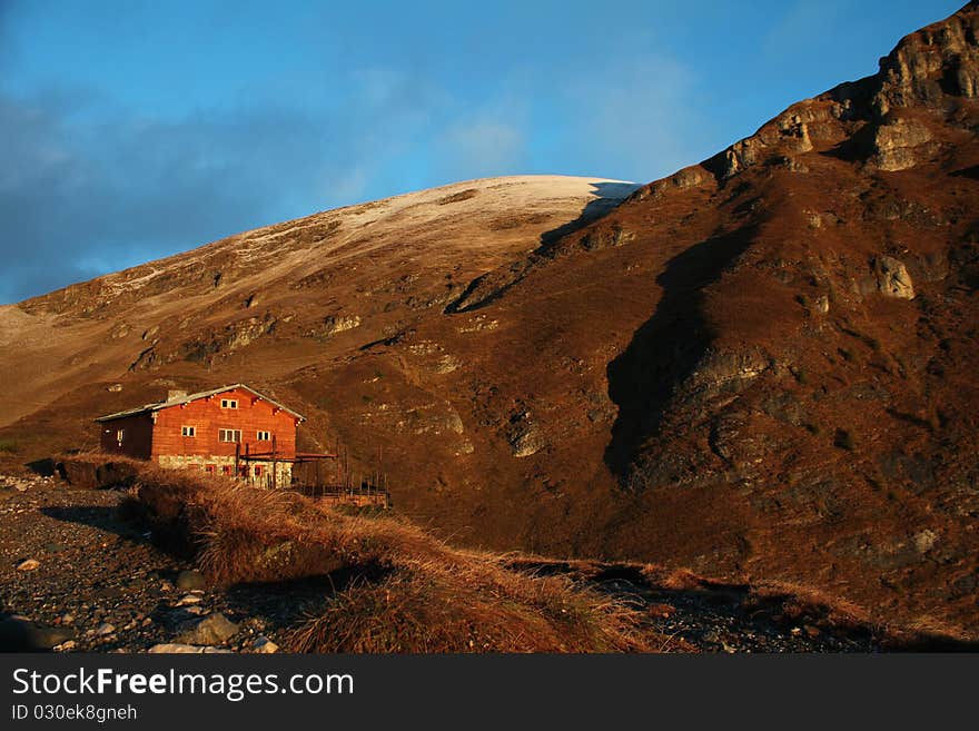 Old wood chalet in the mountains, in the sunrise light.