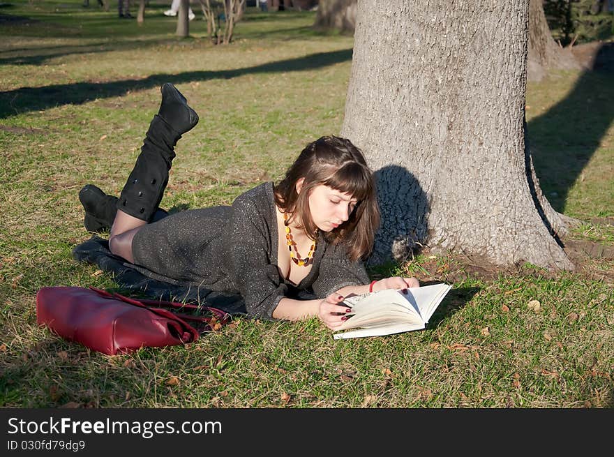 Girl reading while lying in a park on the grass