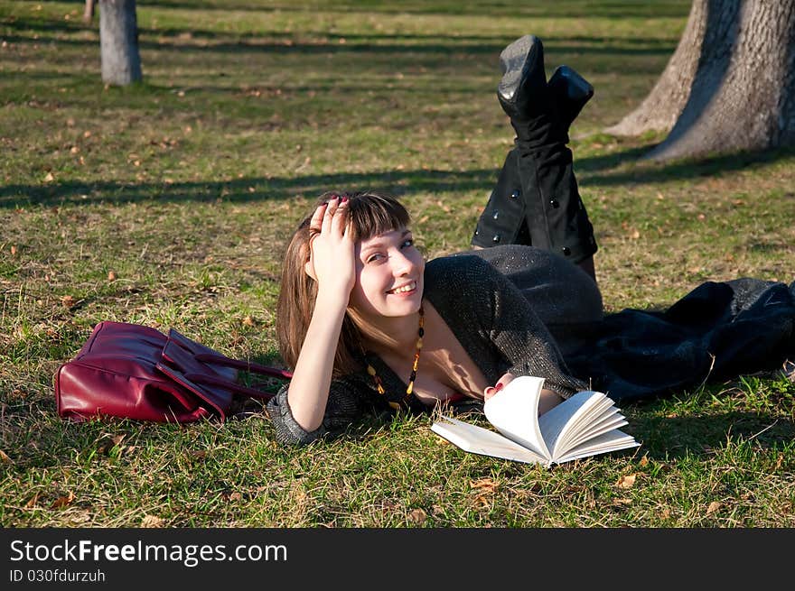 Girl reading while lying in a park on the grass