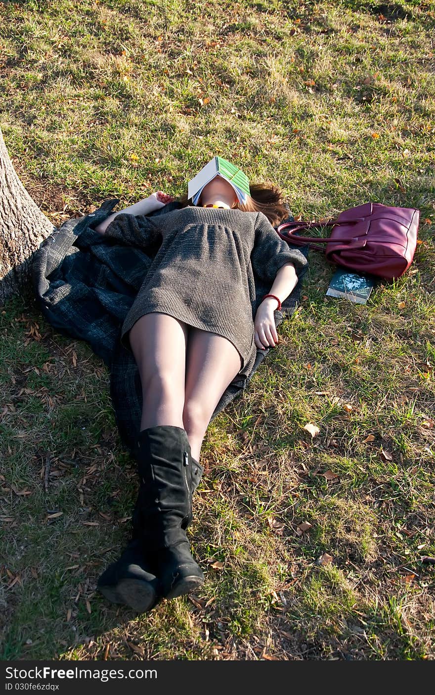 The girl had fallen asleep while reading in the park on the grass. The girl had fallen asleep while reading in the park on the grass