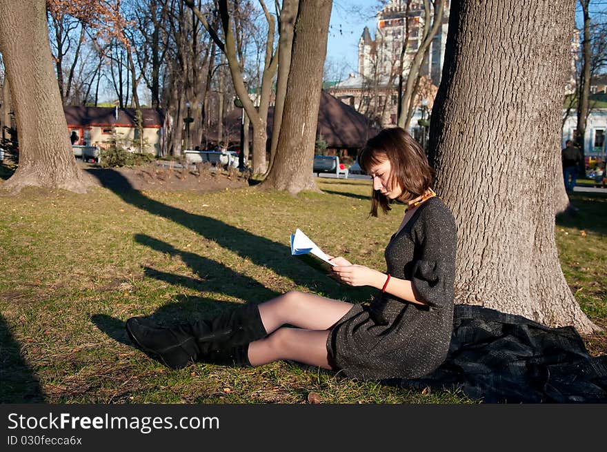 Girl reading while sitting in a park on the grass