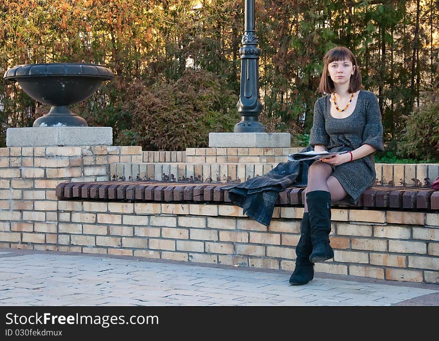 Girl reading a magazine on a park bench. Girl reading a magazine on a park bench