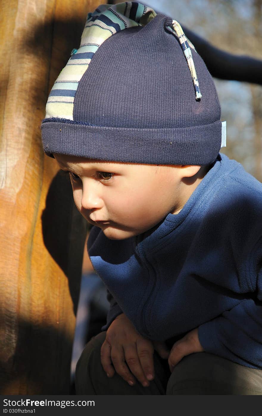 Young boy squatting on a playground wooden construction. Young boy squatting on a playground wooden construction