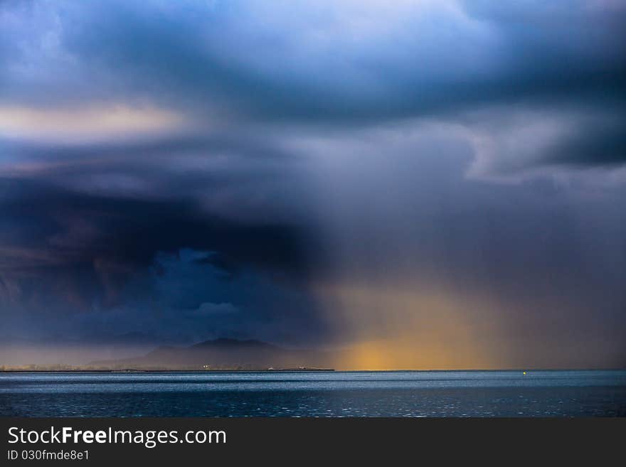 Thunder storm with rain lit by the sun at a lake