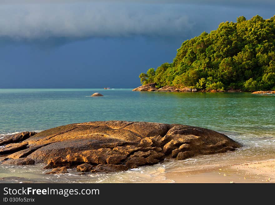 Thunder storm approaching the tropical beach lit by sun. Thunder storm approaching the tropical beach lit by sun