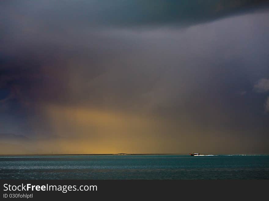 Thunder storm with rain lit by the sun at a lake