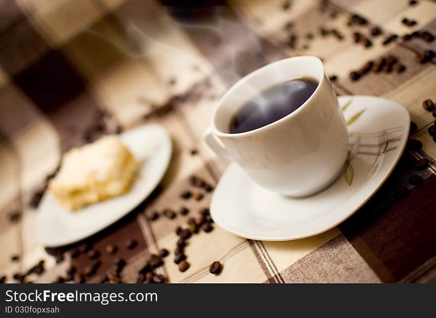 Very hot coffee in cup and cake on table, cake in blurred background. Very hot coffee in cup and cake on table, cake in blurred background