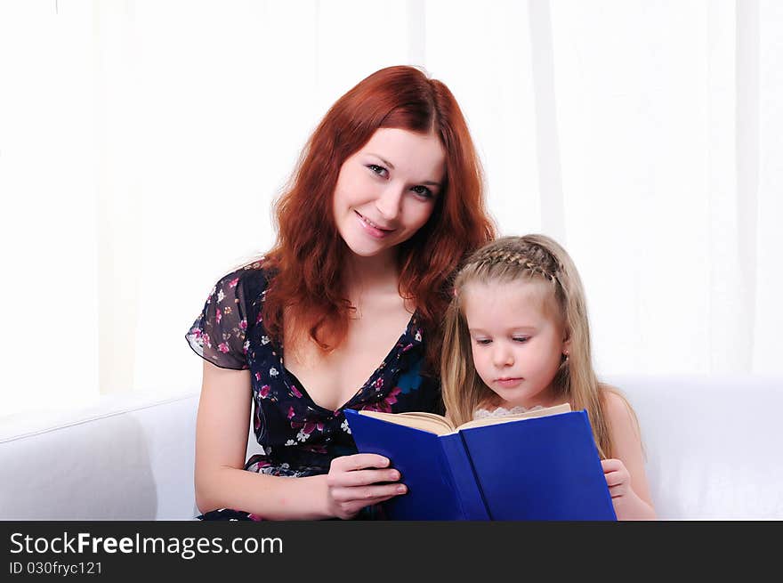 The little girl and her mother read a book together on the couch