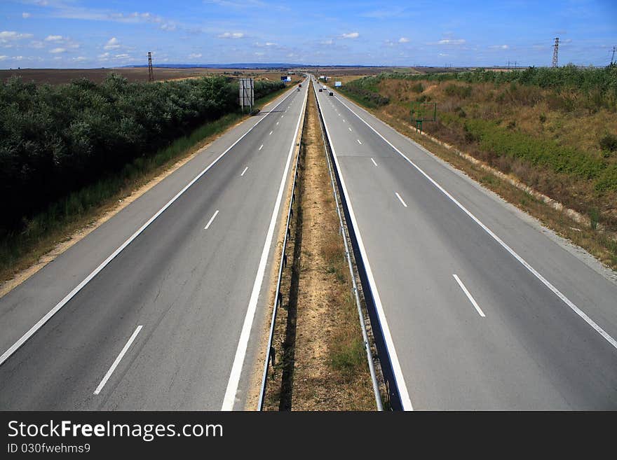 Long road stretching out into the distance under a dramatic blue sky. Long road stretching out into the distance under a dramatic blue sky