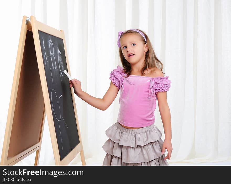 A little girl wrote in chalk on the graphite board. Receive their education.