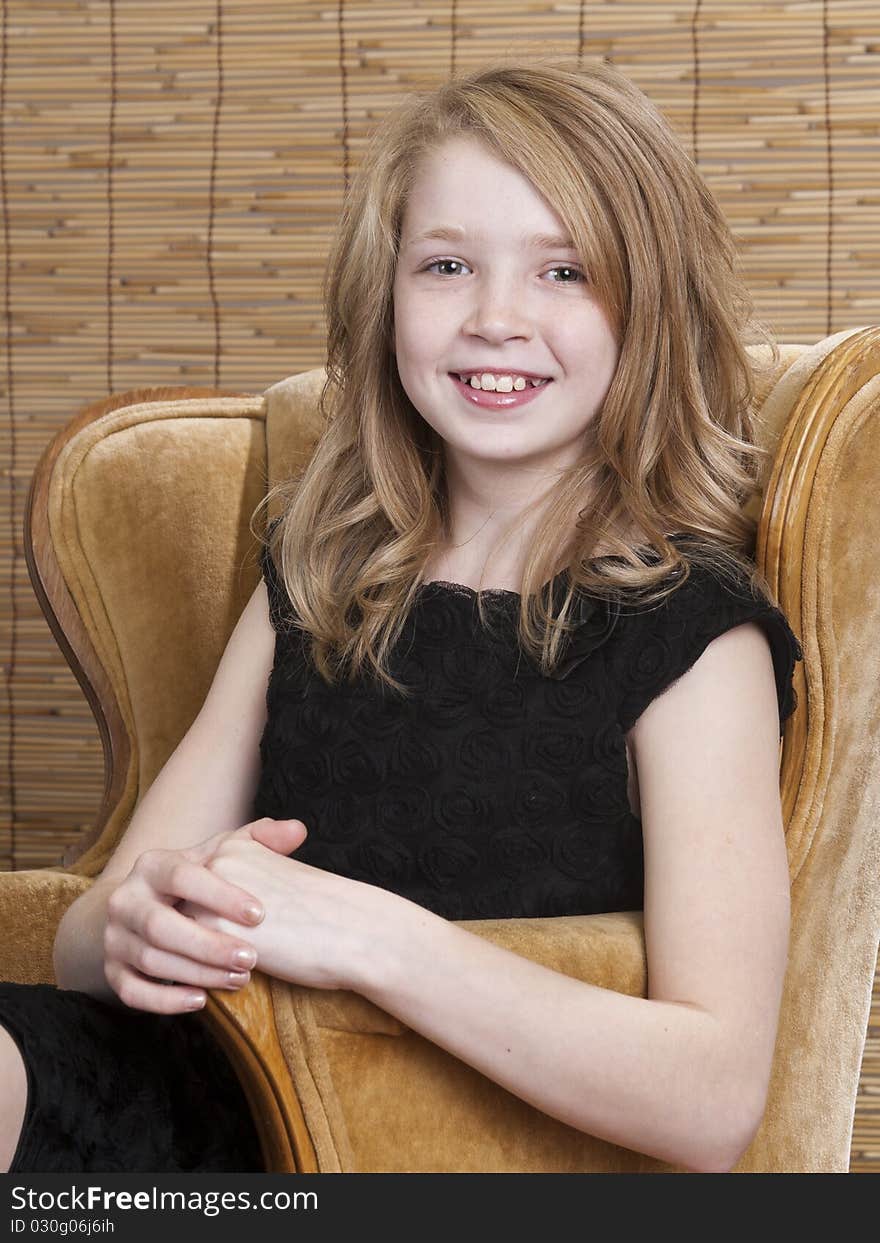 Young preteen girl looking off to the side while sitting in a chair with circle background. Young preteen girl looking off to the side while sitting in a chair with circle background