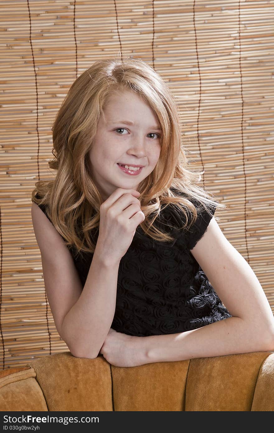 Young preteen girl looking off to the side while sitting in a chair with circle background. Young preteen girl looking off to the side while sitting in a chair with circle background