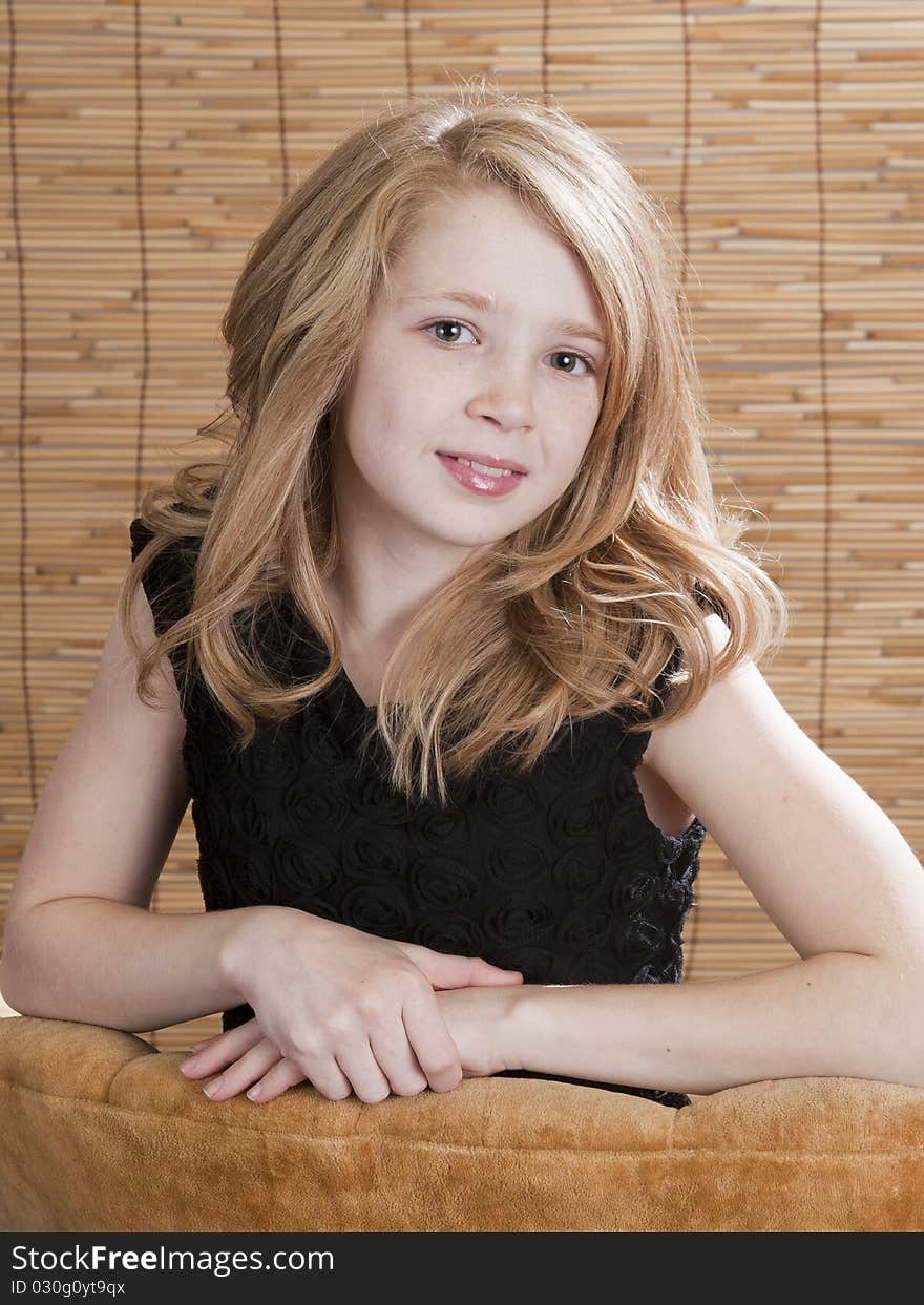 Young preteen girl looking off to the side while sitting in a chair with circle background. Young preteen girl looking off to the side while sitting in a chair with circle background