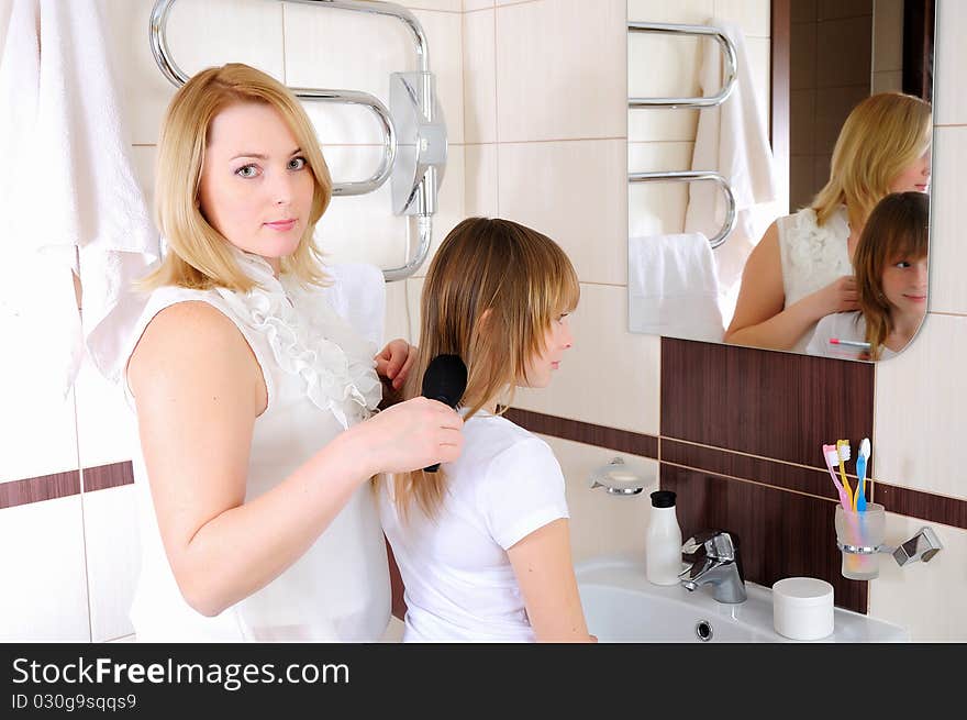 A young girl and her mother take care of the hair in his bathroom