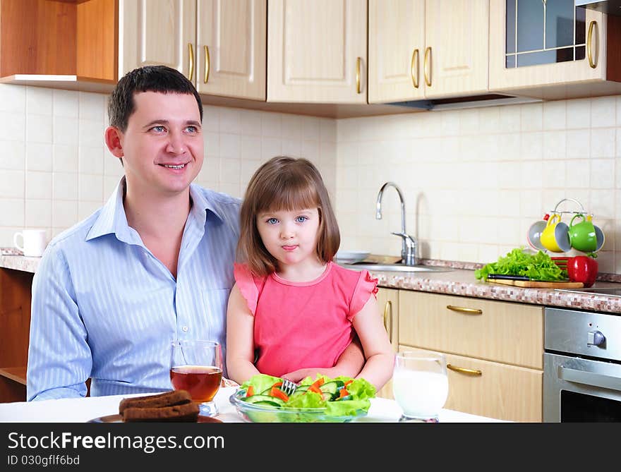 Father and his young daughter eat breakfast together in his kitchen.